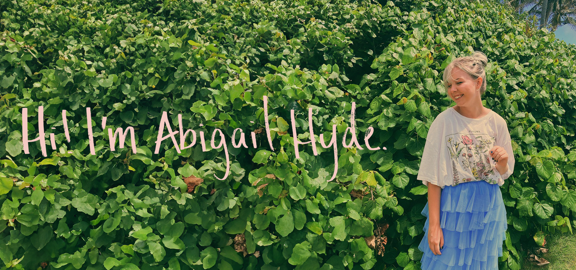 A photo of a young woman, Abigail, smiling in front of a green bush. The phrase 'Hi! My name is Abigail Hyde!' is written across the image in Abigail's handwriting.